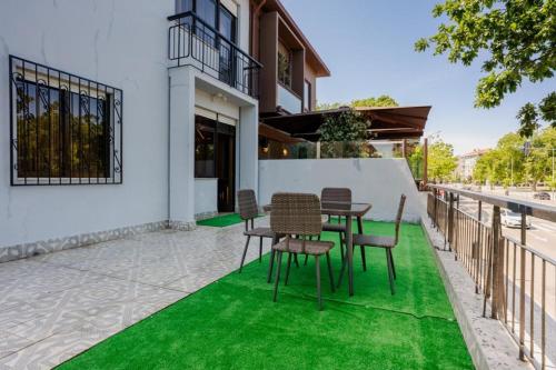 a patio with a table and chairs on green grass at Vikap Guest House in Porto