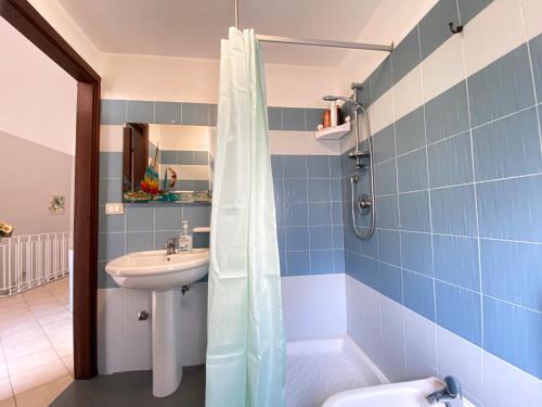 y baño de azulejos azules con lavabo y ducha. en La Ginestra, en Corleone