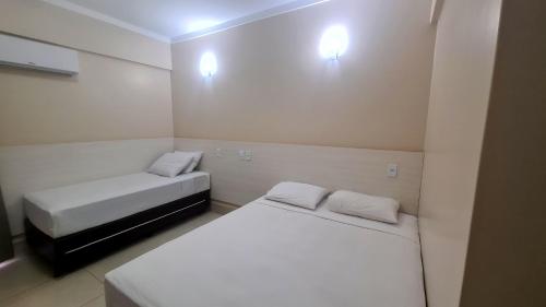 カルダス・ノバスにあるHotel Spazzio diRoma GRATIS entrada Acqua e Splash Caldas novasの白い壁の小さな部屋のベッド2台