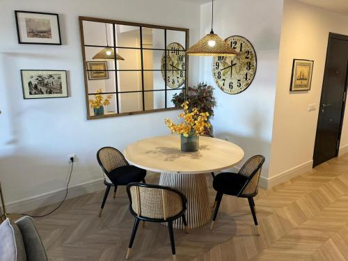 a dining room table with chairs and a clock on the wall at Mirador de Sanlucar 9 in Sanlúcar de Barrameda