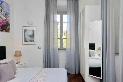 een witte slaapkamer met een bed en een spiegel bij LUXURY APARTMENT VATICANO-S'PETER BASILICA - NETFLIX Wifi - AirCond in Rome