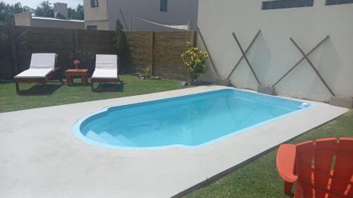 a swimming pool in a yard with two chairs at EL BAGUAL DE MONTE in San Miguel del Monte