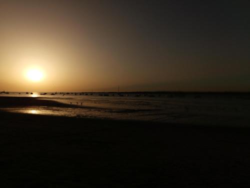 a sunset on the beach with the sun setting at Idalia 19 Atico in Sanlúcar de Barrameda