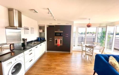 a kitchen with a stove top oven next to a table at Maidenehad Spacious Spectacular and Modern 3 Bedroom 2 Bathroom Penthouse 14 in Maidenhead