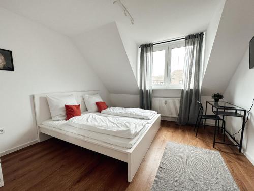 a white bed with red pillows in a room with a window at Design Wohnung im Zentrum von Koblenz in Koblenz