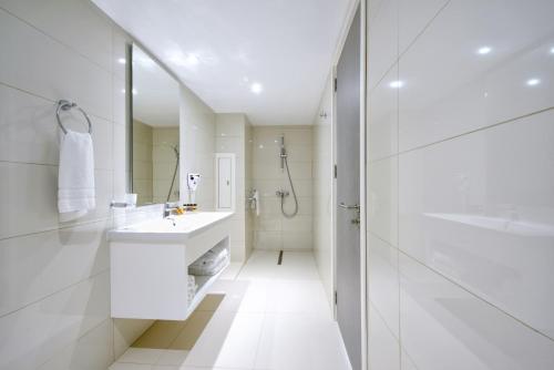 uma casa de banho branca com um lavatório e um chuveiro em River Rock Hotel em Ayia Napa