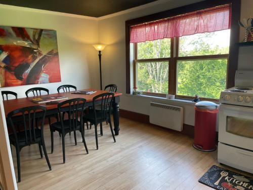 a dining room with a table and chairs and two windows at Auberge La Table d'Hôte in West Brome