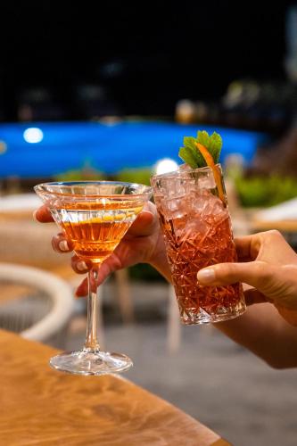 a person holding a drink in a glass at Skiathos Avaton Garden, Philian Hotels and Resorts in Skiathos Town