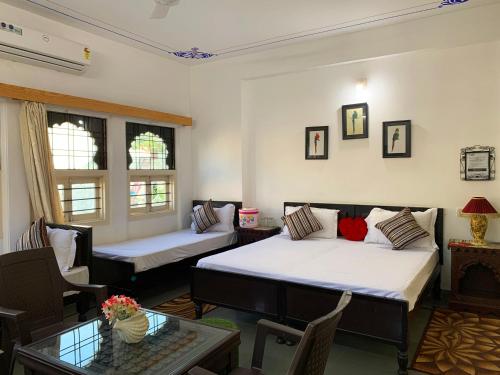 a room with two beds and a table at Gadh Ganesh Homestay in Udaipur