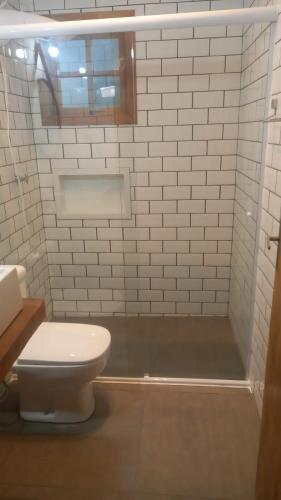 a white bathroom with a toilet and a shower at Pousada Sitieto Voitov in Aluminio