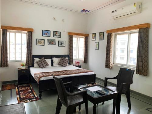 een slaapkamer met een bed en een tafel en stoelen bij Gadh Ganesh Homestay in Udaipur