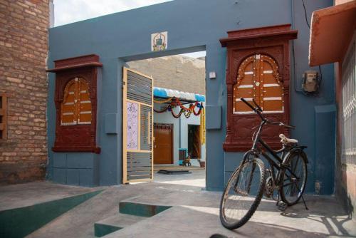 una bicicleta estacionada frente a un edificio azul en Little prince guest house & homestay, en Bikaner