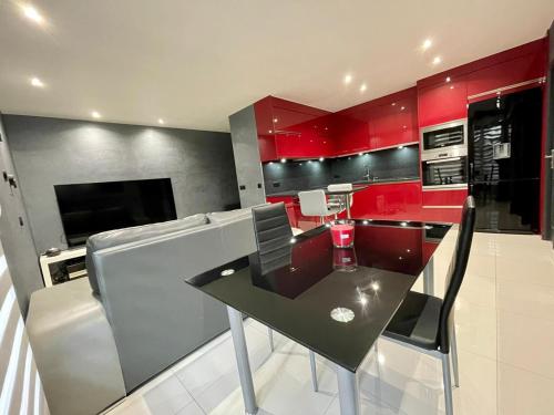 une cuisine avec des armoires rouges et une table et des chaises noires dans l'établissement Ambre&Tiago, à Vaires-sur-Marne