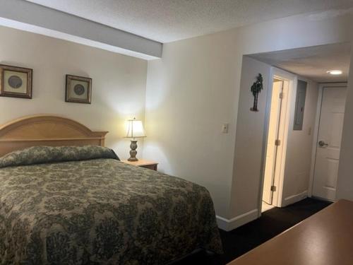 a bedroom with a bed and a lamp and a door at Kingfisher Inn in Myrtle Beach