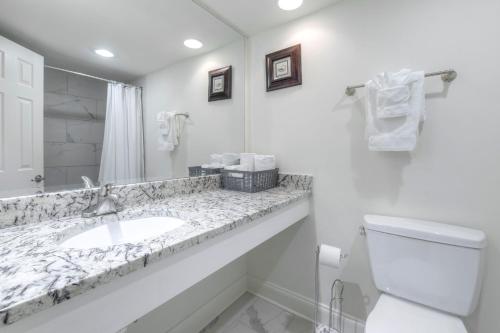 a bathroom with a sink and a toilet and a mirror at Kingfisher Inn in Myrtle Beach