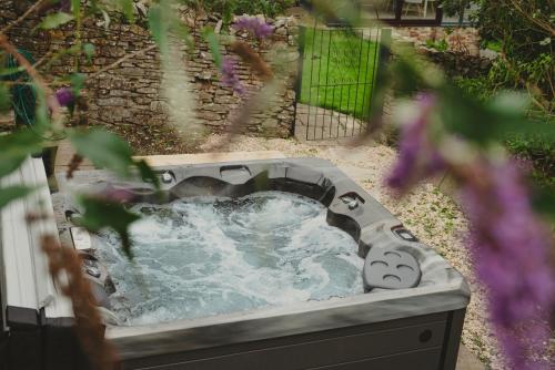 a hot tub in a garden with purple flowers at Timber Hill - Parkfields in Haverfordwest