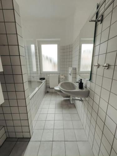 baño blanco con lavabo, bañera y tubermott en Geräumige 3-Schlafzimmer-Wohnung in Koblenz nahe Uni, en Coblenza