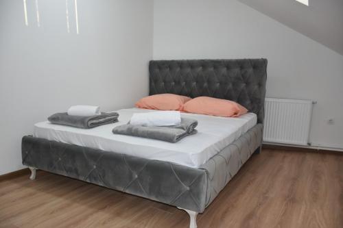- un lit avec une tête de lit noire et des oreillers roses dans l'établissement Bella apartmani, à Požarevac