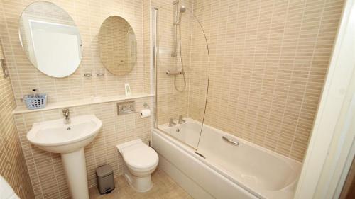 a bathroom with a sink and a toilet and a bath tub at Marina Villas, Trawler Road, Marina in Swansea