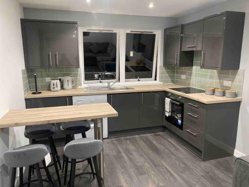 a kitchen with green cabinets and a table and stools at A modern and homely apartment in Crieff