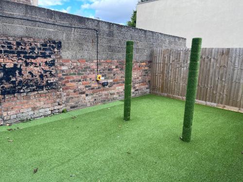 two poles in front of a brick wall with green grass at Humber Maisonette Airy, Modern & Chic! in Goole