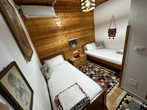 two beds in a small room with wooden walls at Ahmetaj Guest House in Gjirokastër