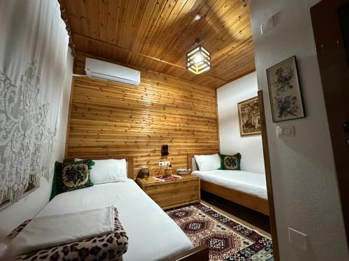 1 dormitorio con 2 camas y pared de madera en Ahmetaj Guest House en Gjirokastër