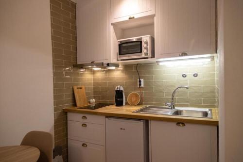 a small kitchen with a sink and a microwave at Casa das Marés 2 in Baleal