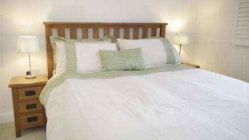 een bed met witte lakens en kussens en 2 lampen bij Witsend, Horton in Port-Eynon