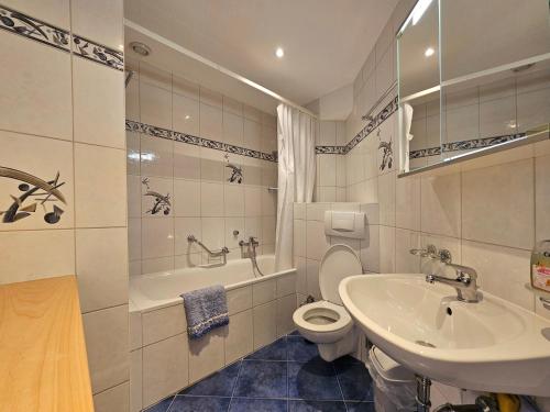 a bathroom with a sink and a toilet and a tub at Dominic B1 in Saas-Fee