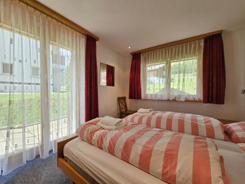 a bedroom with two beds and large windows at Dominic B1 in Saas-Fee