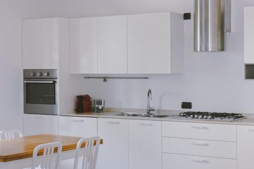 a white kitchen with white cabinets and a wooden table at Casa Lobe - Charming apartment in village centre in La Morra