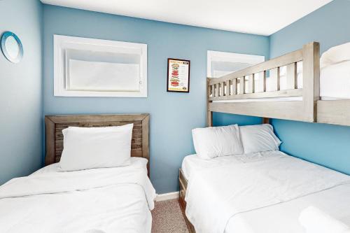 two beds in a room with blue walls and bunk beds at Vanodi Landing in North Topsail Beach