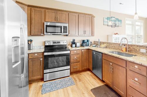 a kitchen with wooden cabinets and stainless steel appliances at Vanodi Landing in North Topsail Beach