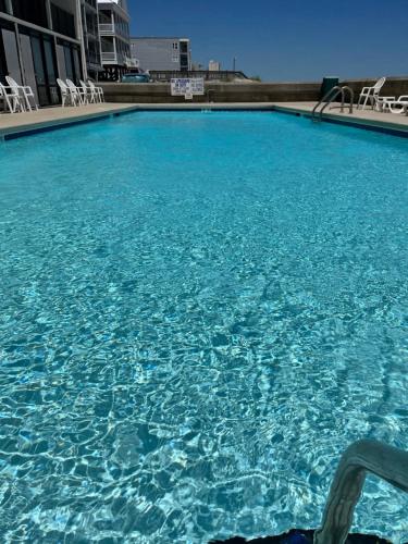 duży basen z niebieską wodą i białymi krzesłami w obiekcie Kingfisher Inn w mieście Myrtle Beach