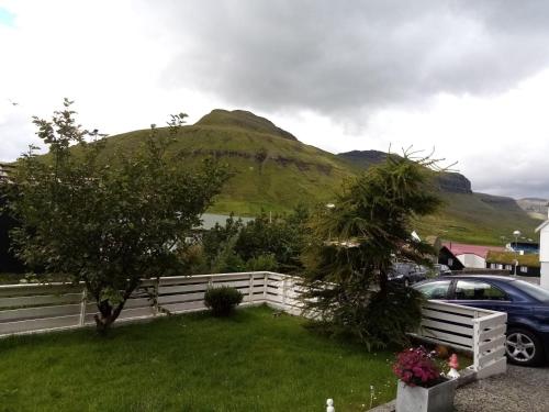 a car parked in a yard with a fence and a mountain at Experience unique Faroe Islands holiday home by the sea with great views, fully equipped kitchen and reliable Wi-Fi 