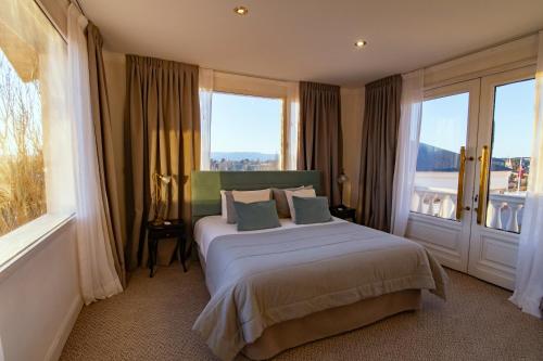 a bedroom with a large bed with a window at Lagos Del Calafate in El Calafate
