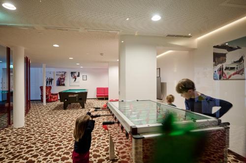 2 Jungs spielen Billard in einem Zimmer mit Billardtisch in der Unterkunft Hotel Austria in Lech am Arlberg