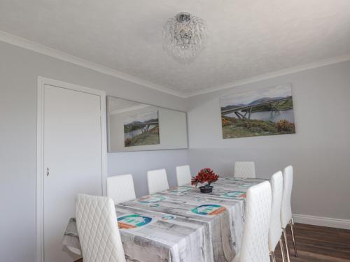 a dining room with a table and white chairs at Beachview in Oldshoremore