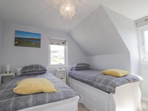 two beds in a white room with a chandelier at Beachview in Oldshoremore