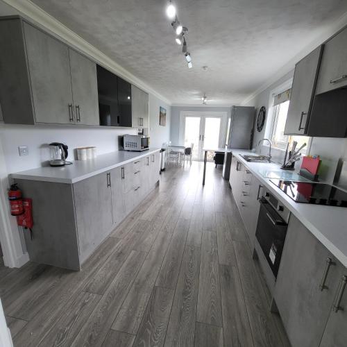 a large kitchen with white cabinets and a wooden floor at Beachview in Oldshoremore