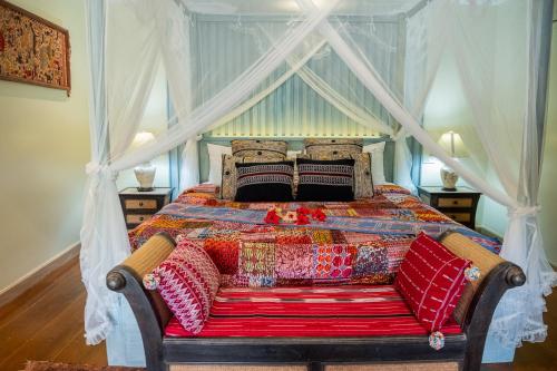 a bedroom with a canopy bed with a colorful quilt at Kanlaya's Eyrie, Luxury Homestay in Pang Mapha