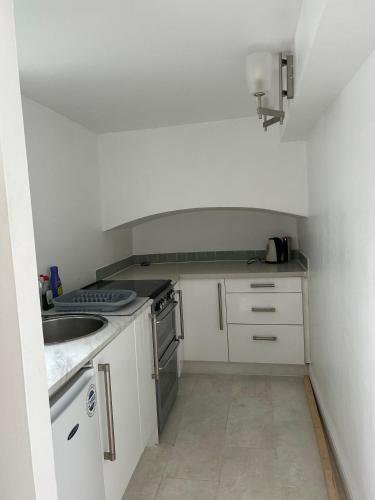 uma pequena cozinha com armários brancos e um lavatório em West Kensington em Londres