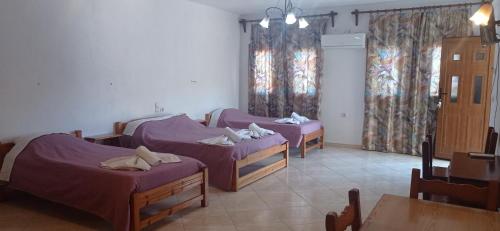 Habitación con 3 camas, sábanas moradas y mesa. en Smile Stella Studios, en Skopelos Town