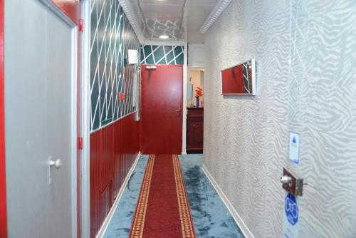 a hallway with a red door and a red floor at Hôtel Aux Armes de Belgique in Lourdes