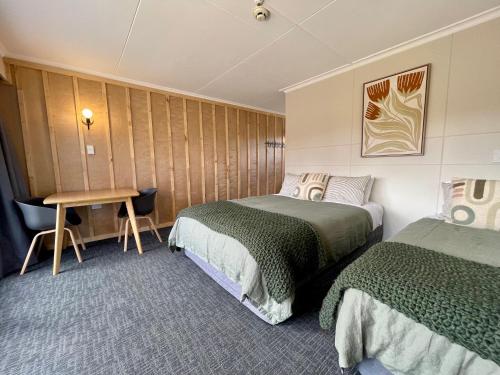 a hotel room with two beds and a table at Te Anau Lakefront Backpackers in Te Anau