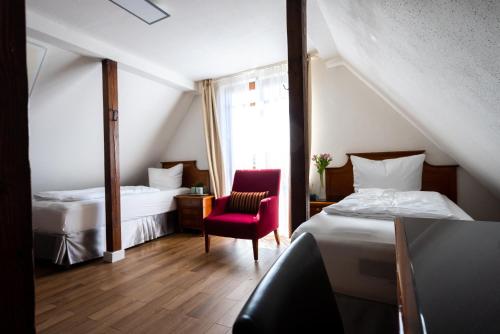 斯圖加特的住宿－CityHotel Feuerbach，酒店客房,设有两张床和一张红色椅子