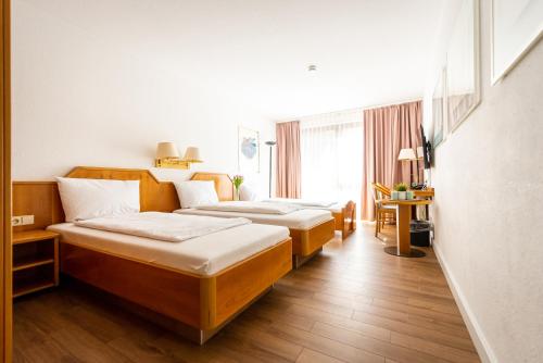 a hotel room with three beds and a window at CityHotel Feuerbach in Stuttgart