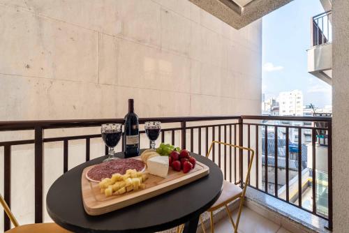 uma mesa com um prato de queijo e vinho numa varanda em Rover Centro em São Paulo