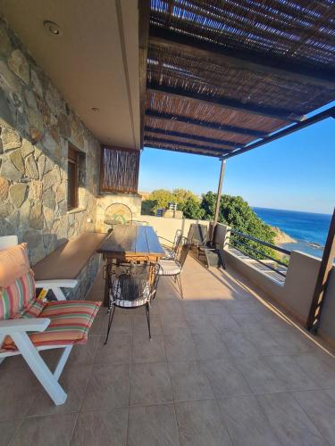 a patio with a table and chairs and the ocean at VILLA PETRINO in Tsoútsouros